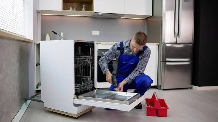 Technician working on an open dishwasher in a residential kitchen