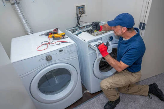 Technician servicing the upper panel of a laundry appliance beside a dryer