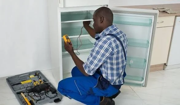 Technician testing a refrigerator with a diagnostic meter