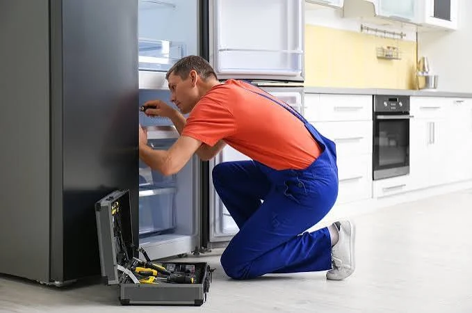Appliance repair technician inspecting refrigerator
