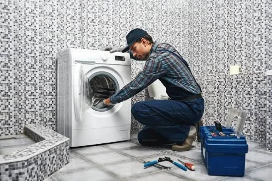 Technician inspecting a front-loading washing machine in a tiled laundry room
